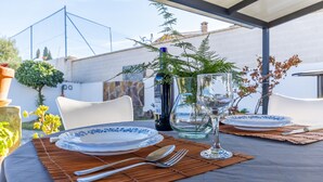 Een terras met eethoek, gedekt voor twee personen, met vrij uitzicht op de lucht en een potplant.
