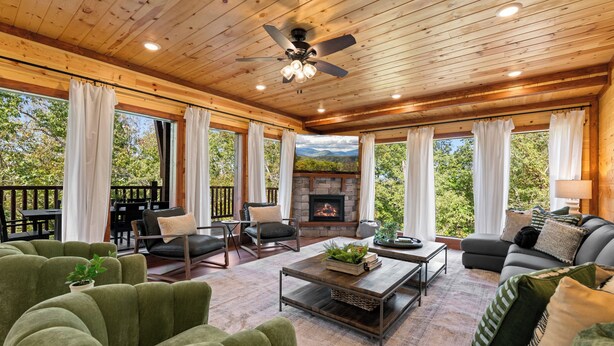 A spacious living room with a fireplace, green upholstered furniture, and a view of the outdoors. - Brand New Greenleaf Lodge ~Indoor Pool ~ Hot Tub (Sevierville)