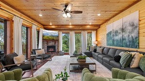 A cozy living room with leather sofas, a fireplace, and a large painting of a forest. - Brand New Greenleaf Lodge ~Indoor Pool ~ Hot Tub (Sevierville)