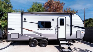 A white RV with "Autumn Ridge" branding, a sliding door, and a small window. - The Happy Camper - Cozy RV sleeps 4, with WiFi, in beautiful Ojai (Ojai)