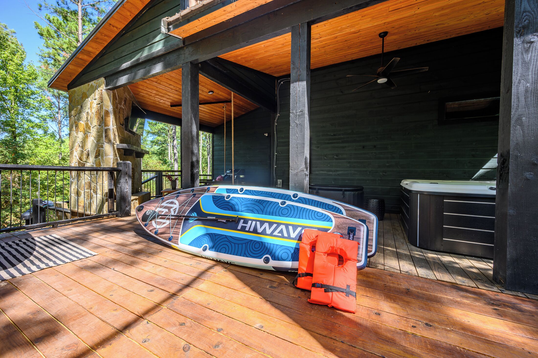 A wooden deck with a floating hot tub, a life preserver, and a stone pillar.