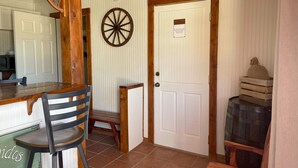 A room with a wooden bar, a wheel, a door with a sign, and a barrel. - Big Bend Lodging at Ten Bits Ranch - Room #15 -  Freight Office (Terlingua)