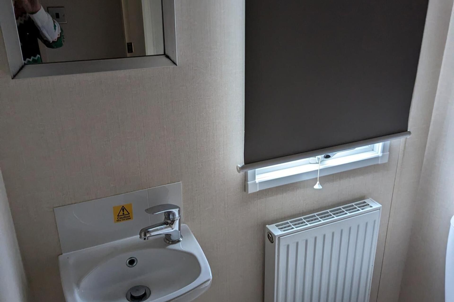 A bathroom with a sink, mirror, and a radiator.