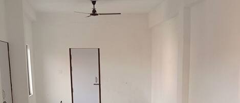 A spacious room with a patterned floor, a ceiling fan, and a door at the far end.