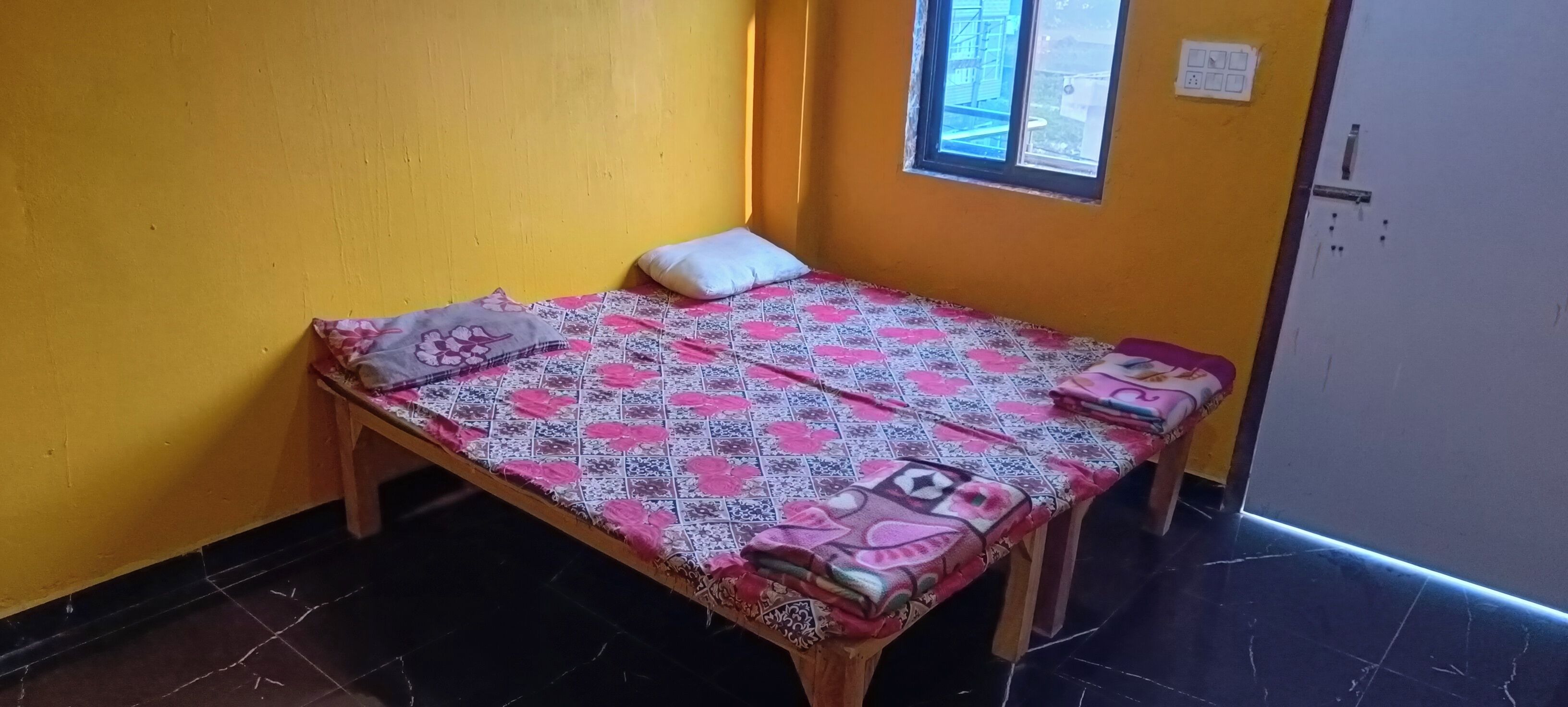 A small room with a bed, a window, and a door.