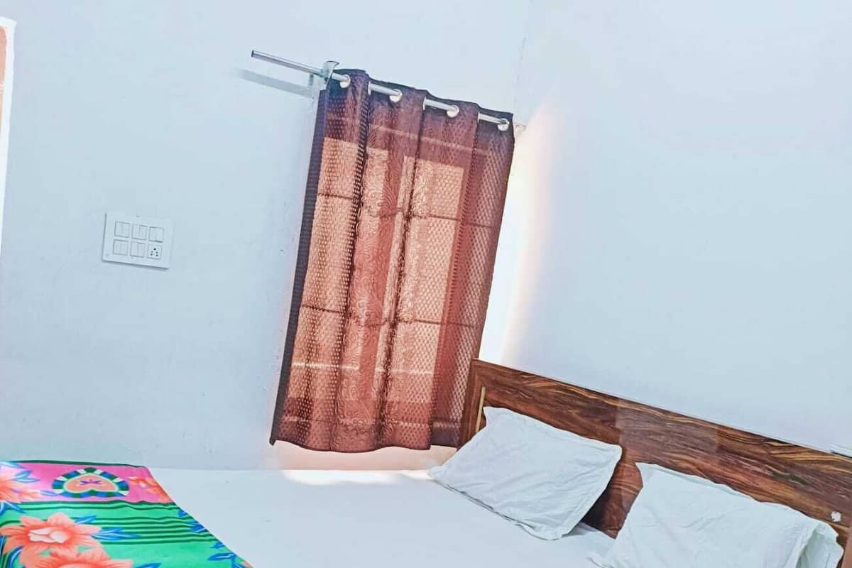 A room with a bed, a wall-mounted air conditioner, and a window with a curtain.