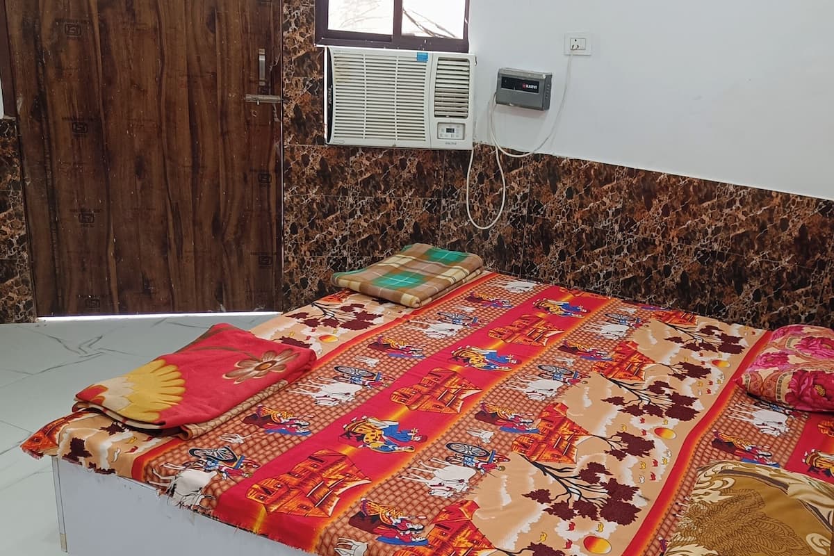 A room with a bed, a wooden door, a marble-patterned wall, and an air conditioning unit.
