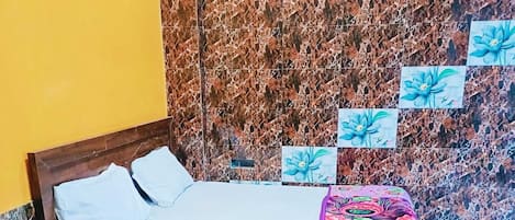 A bedroom with a wooden bed, a marble-patterned wall, and a bedspread with a floral design.