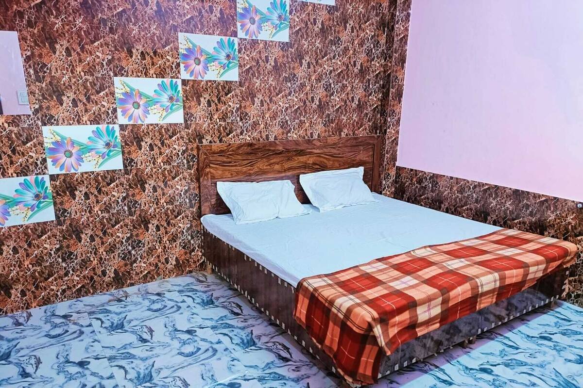 A bedroom with a bed, a wooden headboard, and a marble-patterned wall.