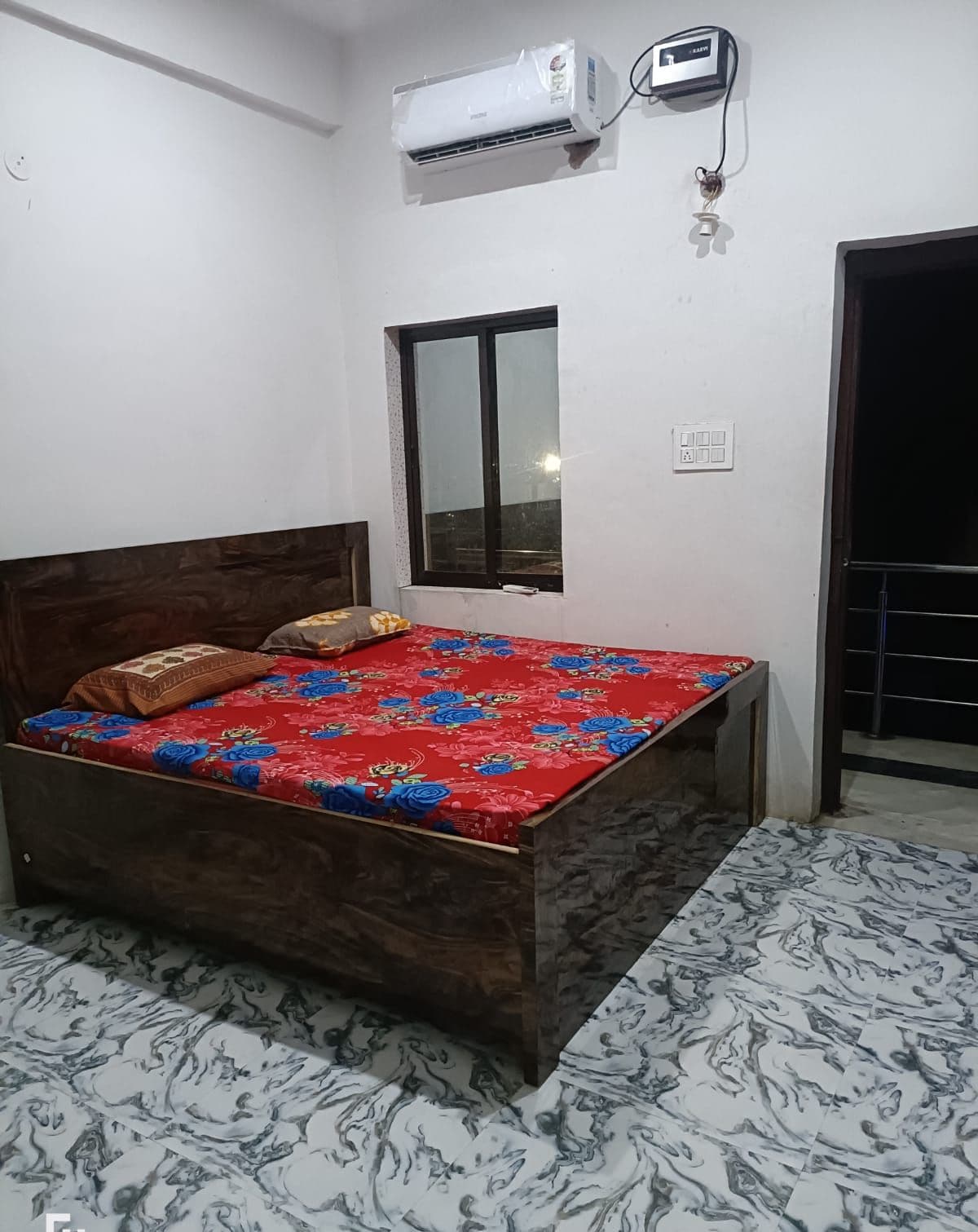A bedroom with a wooden bed, a window, an air conditioner, and a patterned floor.