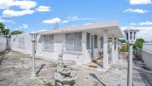 A white building with a covered patio, a decorative fountain, and a white railing. - Cozy Retreat in San Juan

 (san juan)