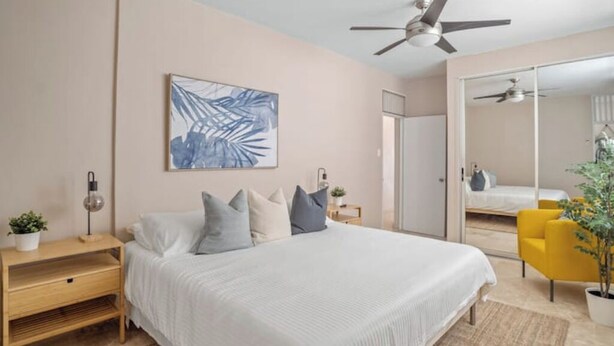 A bedroom with a bed, bedside table, lamp, and a large mirror. - Cozy Retreat in San Juan

 (san juan)