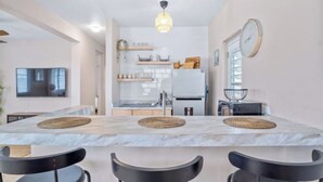 A modern kitchen with a marble countertop, black chairs, and a hanging light fixture. - Cozy Retreat in San Juan

 (san juan)