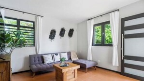 Una sala de estar moderna con un sofá, una mesa de centro de madera y una planta en maceta.