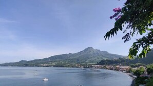 Vista costera con una montaña al fondo, mar tranquilo y un pequeño bote.