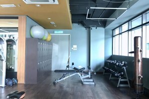 Ein Fitnessraum mit Trainingsgeräten, Schließfächern und einem großen Fenster.