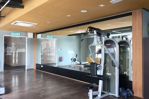 A gym with exercise equipment, a mirror, and a wooden floor. - Homesuite' Home at Riverson Soho (Kota Kinabalu)