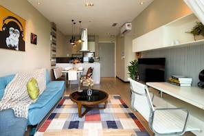A modern living room with a sofa, coffee table, and a TV. - Homesuite' Home at Riverson Soho (Kota Kinabalu)