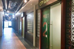 Um corredor com uma porta verde identificada com a inscrição 'MEET 2' e uma placa acima.