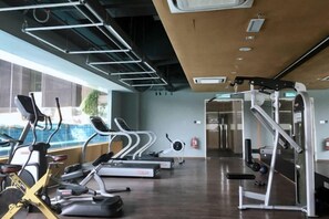 Une salle de sport équipée de tapis de course, de vélos elliptiques et d'appareils de musculation.