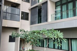A multi-story building with balconies, large windows, and a small tree in the foreground. - Homesuite' Home at Riverson Soho (Kota Kinabalu)