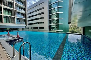A swimming pool with a modern building in the background. - Homesuite' Home at Riverson Soho (Kota Kinabalu)