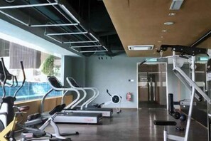 Une salle de sport équipée de tapis de course, de vélos d’appartement et d’appareils de musculation.