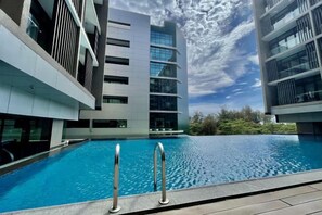 A swimming pool with metal railings, surrounded by modern buildings with balconies and large windows. - Homesuite' Home at Riverson Soho (Kota Kinabalu)