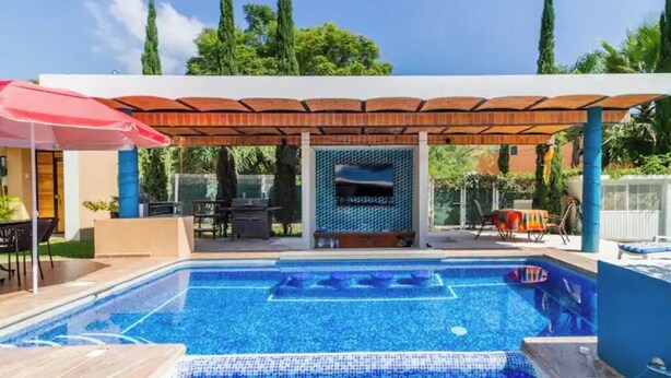 A swimming pool with a covered patio area, outdoor furniture, and a view of the surrounding greenery. - Lovely bungalow with WiFi in Chapala Haciendas (Chapala Haciendas)