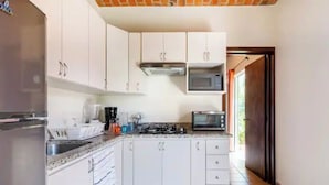 A kitchen with white cabinets, a microwave, a stove, and a refrigerator. - Lovely bungalow with WiFi in Chapala Haciendas (Chapala Haciendas)