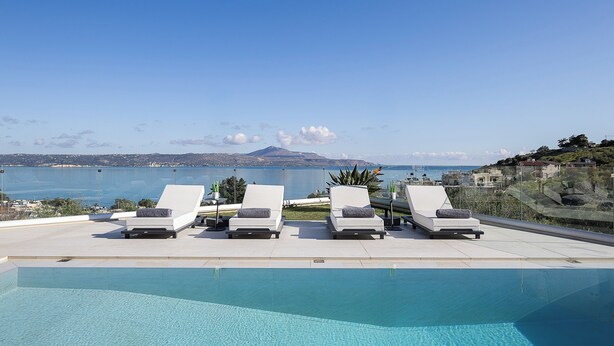 A rooftop pool area with four lounge chairs and a clear view of the sea and mountains. - Kalyves Royal Villa (Apokoronas)