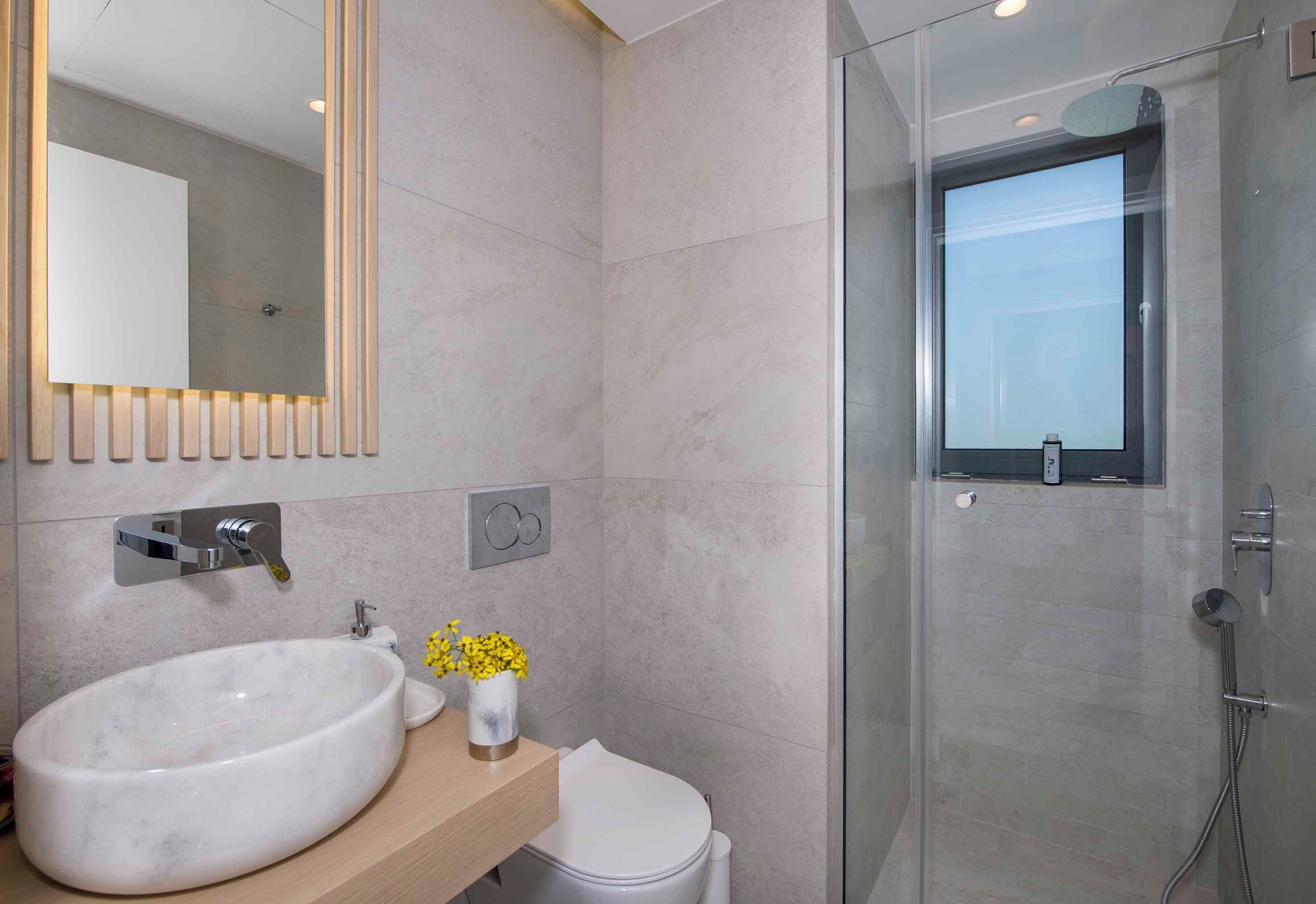 Une salle de bain moderne avec un grand lavabo ovale, des toilettes et une douche à parois de verre.