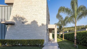 A modern building with a stone facade, a paved pathway, and well-maintained greenery. - Kalyves Royal Villa (Apokoronas)