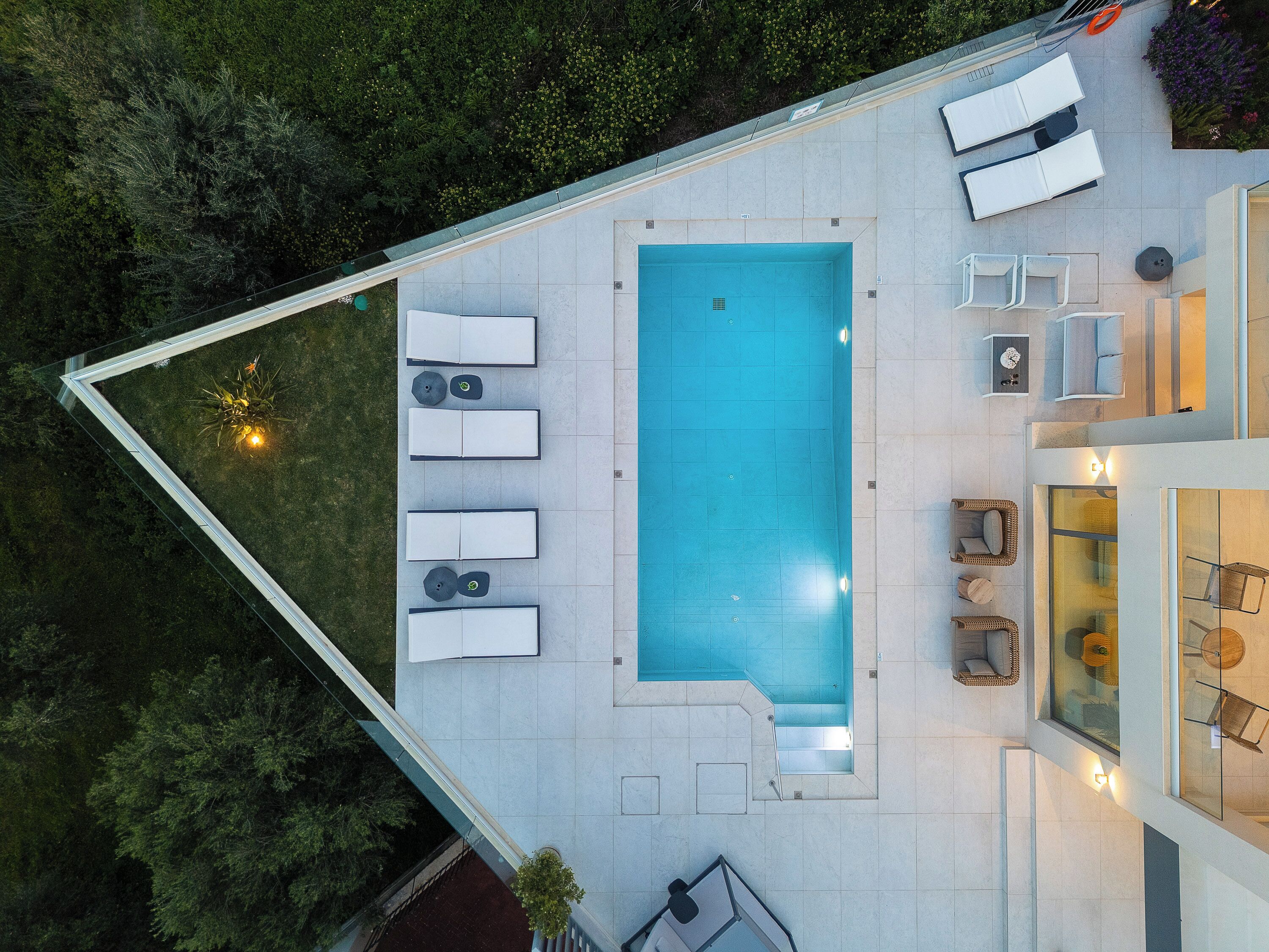 A rooftop pool area with lounge chairs, a swimming pool, and a glass-enclosed dining area.
