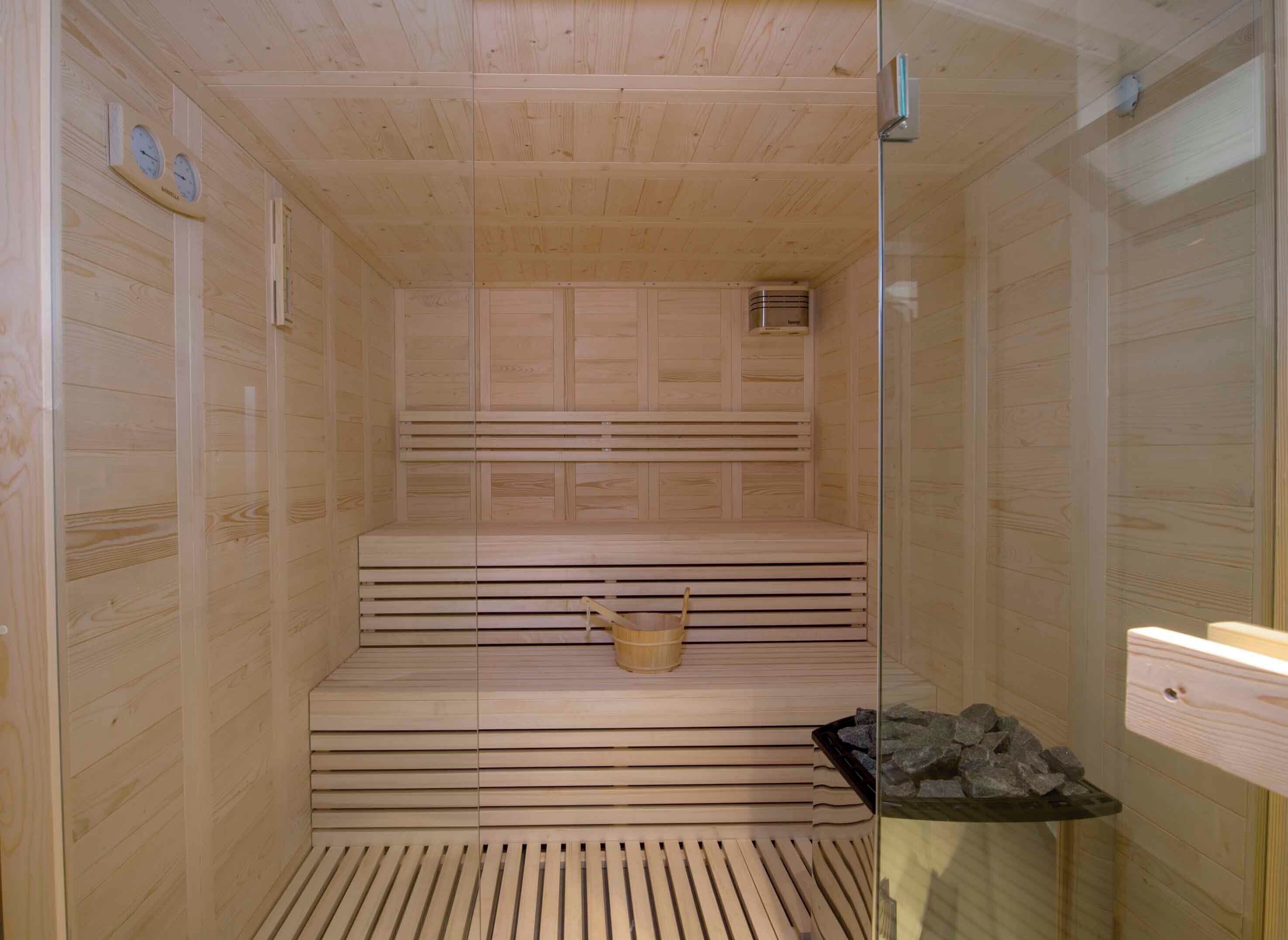 A sauna with wooden benches and a glass door.