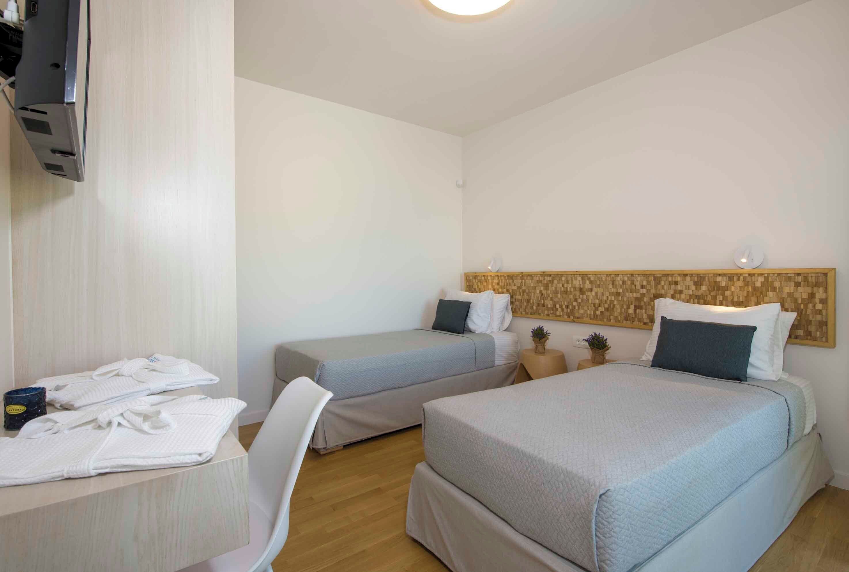 Een hotelkamer met twee bedden, een bureau en een televisie.