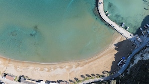 An aerial view of a coastal area with a curved road, clear turquoise waters, and a sandy beach. - Kalyves Royal Villa (Apokoronas)