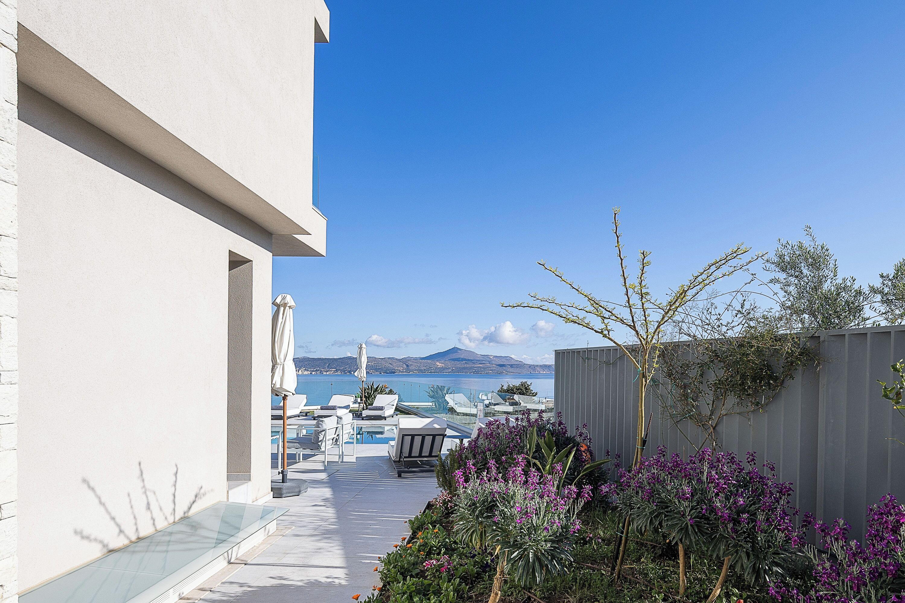 A modern outdoor pool area with lounge chairs and a view of the sea.