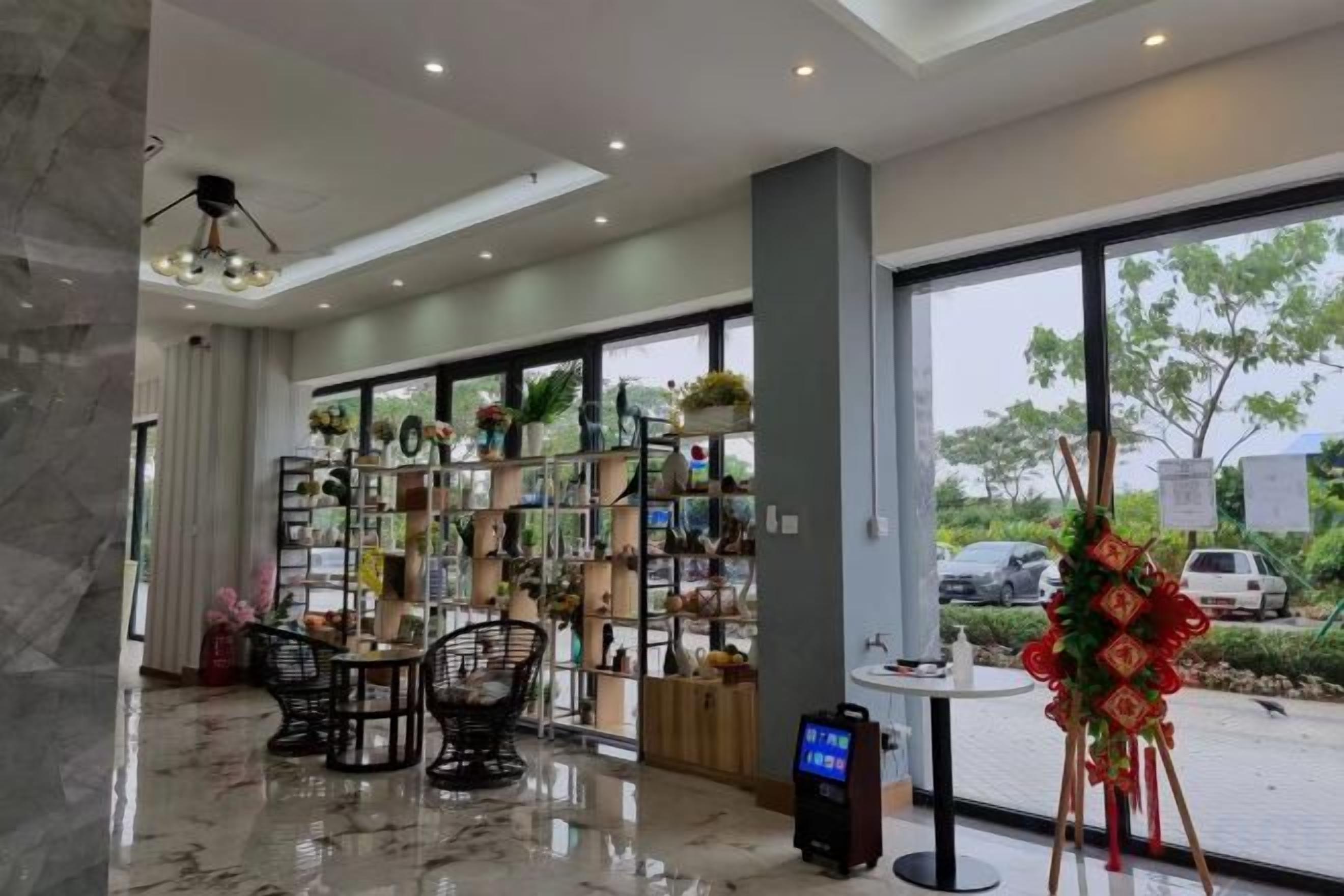 A hotel lobby with a reception desk, seating area, and large windows offering a view of the outdoors.