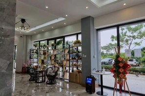 Eine Hotelhalle mit einer Rezeption, einer Sitzecke und großen Fenstern mit Blick ins Freie.