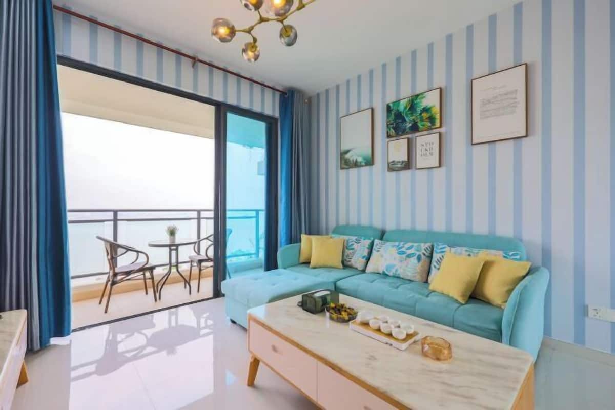 Une pièce comprenant un canapé, une table basse et un balcon avec des chaises.