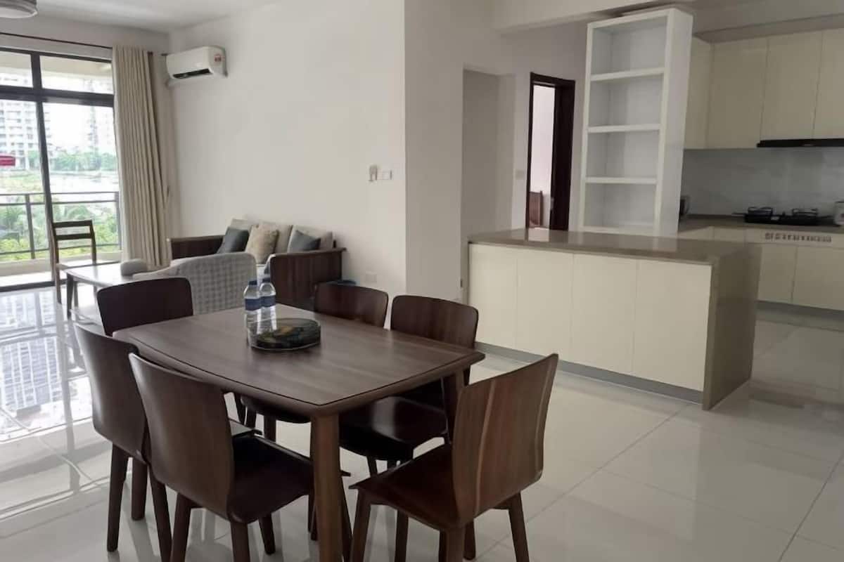 Une cuisine moderne avec des meubles blancs, un four encastré et un coin repas comprenant une table et des chaises en bois.