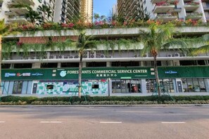 Un centro comercial con varias tiendas, un toldo verde y una palmera en primer plano.