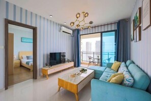 Una sala moderna con sofá, mesa de centro, televisor y un balcón con vistas.