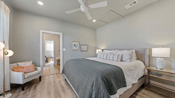 A bedroom with a large bed, a ceiling fan, and a bedside table with a lamp. - Comfortable walk to Magnolia & Just a short drive to Baylor (Waco)
