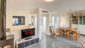Un salon moderne avec une cheminée, un coin repas avec des meubles en bois et une cuisine équipée de placards et d’une cuisinière.