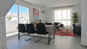 En moderne stue med spiseområde, store vinduer og udsigt over byen.