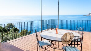 Mesa redonda com cadeiras e uma garrafa em um terraço com vista para um corpo de água.