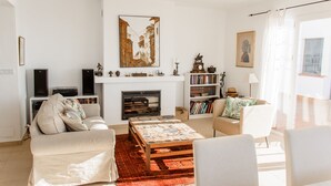 Uma sala de estar com lareira, estante de livros, televisão e uma grande pintura na parede.