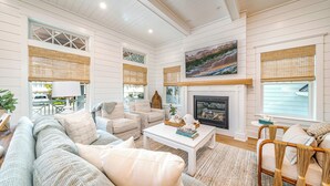A spacious living room with a fireplace, striped sofas, and a large painting above it. - Rooftop Deck & Ocean Views—Luxury 5BR/4.5BA  Single Family, Across from Beach! (Ocean City)